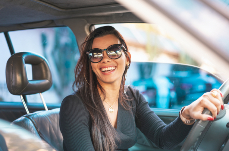 Woman smiles as she sits behind the steering wheel of a new car.
