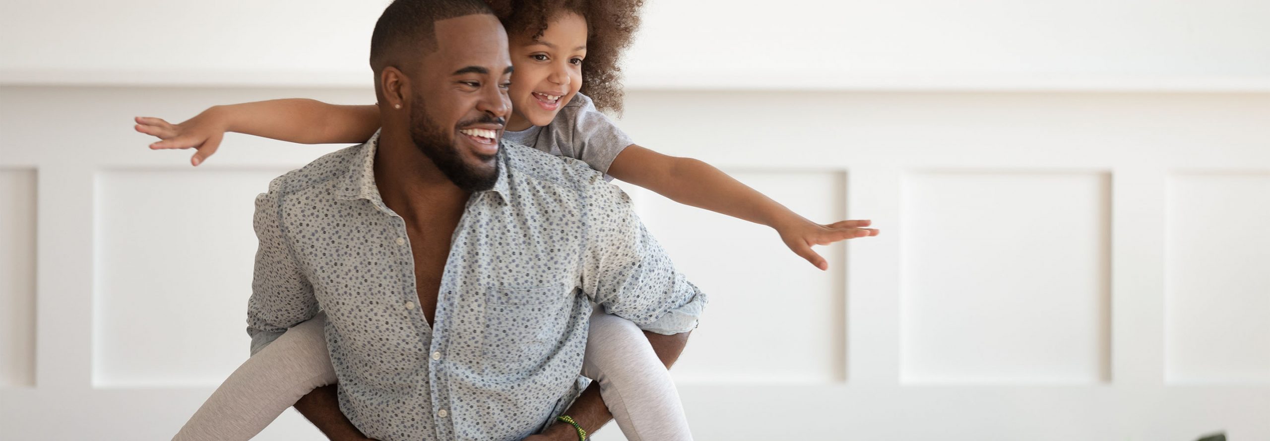 A health plan member gives a young girl a piggyback ride.